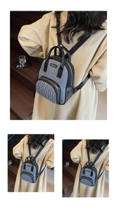Close-up of the grey fabric backpack with quilted front zipper pocket and black leather trim