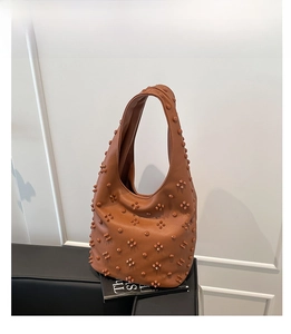 Detailed view of brown leather hobo bag with vintage star rivets and metallic studs