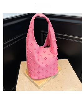 Close-up of pink hobo tote bag with textured pebbled leather and unique 3D stud details