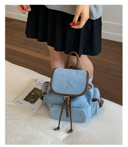 Detailed shot of blue denim backpack with brown leather trim and drawstring closure