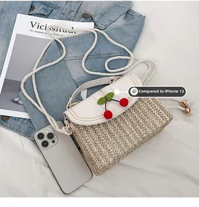 Miniature woven straw bag with cherry detail compared to an iPhone 12 for scale