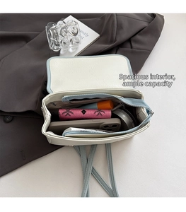Detail view of the spacious inner compartment of the beige leather bag with organized items