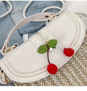 Detail of white leather handbag with cherry charm and cotton rope woven strap