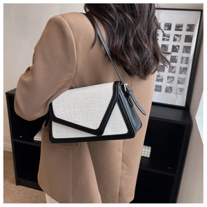 Detail of crocodile pattern texture on a minimalist black and white shoulder bag