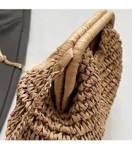 Détail du sac en paille tressée avec chaîne en métal doré et texture de tissage fin