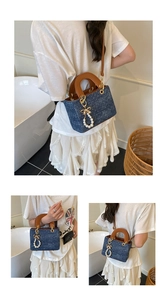 Detail of light blue denim tote bag with leather handles and pearl bow charm