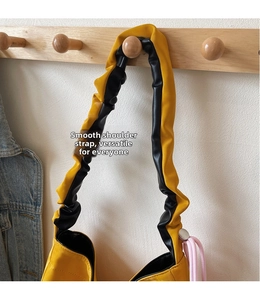 Detail of a yellow and black tote bag featuring ruched strap and pink rope accent