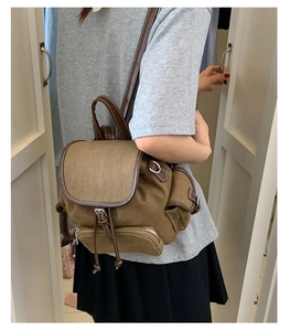 Detail view of the drawstring closure and leather trim on this vintage canvas backpack