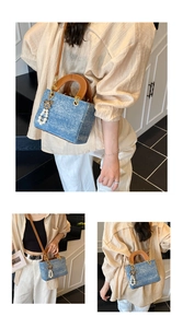 Detail view of denim handbag with round brown handles and pearl butterfly pendant