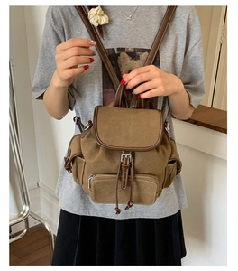 Detail showing vintage brown canvas backpack with leather trim and magnetic buckle flap