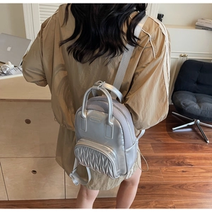 Close-up of silver mini backpack with pleated metallic texture and mesh side detailing