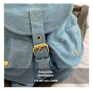 Close-up of golden metal buckle and stitching on blue denim backpack details