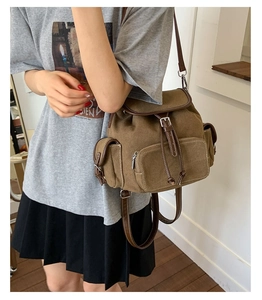 Detail of vintage canvas backpack with brown leather trim and drawstring closure