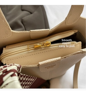 Detail of cream bucket bag with smooth golden zipper and elegant scarf decoration