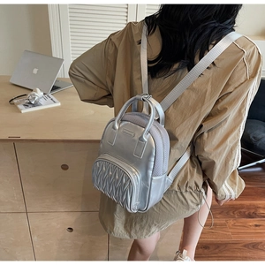 Detail of silver metallic mini backpack with mesh texture and pleated front pocket