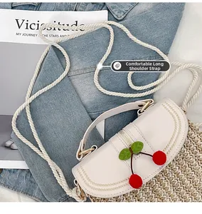 Detail of woven straw bag with red cherry accents and a thick braided white rope strap