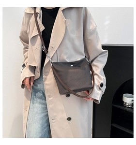 Sac seau tissé marron porté avec un trench beige pour un look décontracté et chic