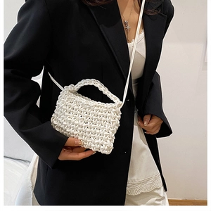 Detailed view of white woven crossbody bag with artistic thick cord knot texture