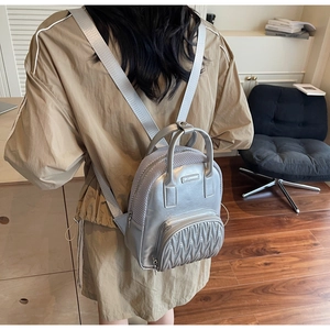 Macro detail of silver PU leather mini backpack with quilted pocket and top handle