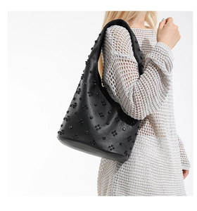 Detailed view of black litchi pattern leather bag featuring 3D floral accents and studs