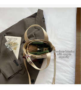Top view of open beige bucket bag showing spacious interior with cosmetics and accessories