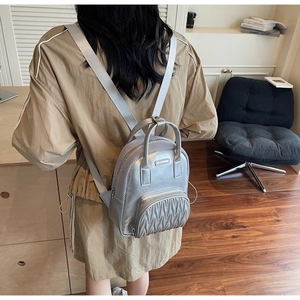 Detail of silver mini backpack showing wave-quilted texture and metallic finish leather