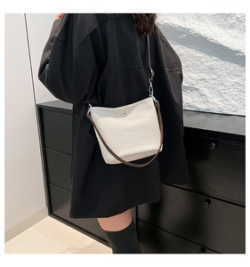Détail d'un sac seau blanc texturé avec bandoulière marron porté par un mannequin