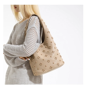 Detail of vintage beige underarm bag with 3D floral rivets and pebbled leather texture