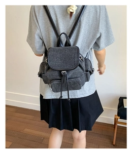 Detail of dark grey vintage canvas backpack with black leather straps and metal buckle