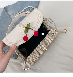 Detail view of woven straw box bag interior with red cherry charm and cotton rope strap