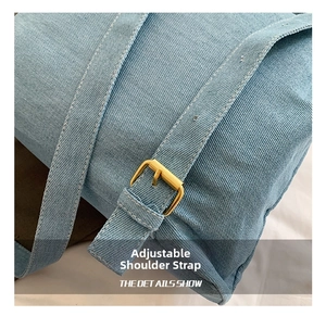 Detailed close-up of light blue denim backpack strap with golden adjustable metal buckle
