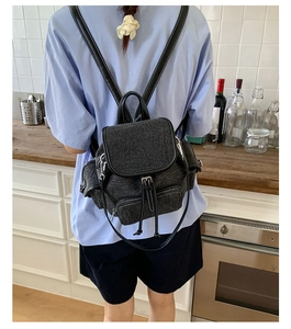 Detail view of large capacity dark grey denim backpack with drawstring closure and straps