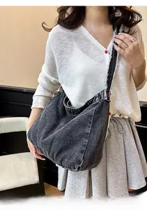 Détail du sac hobo en jean gris délavé avec bandoulière effilochée et grande capacité