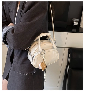 Chic off-white leather pillow bag with baseball charm shown on a model's shoulder