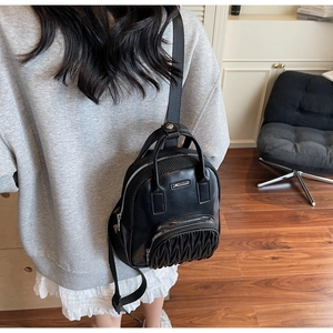 Detail of black mini backpack featuring elegant matelassé stitching and metal logo