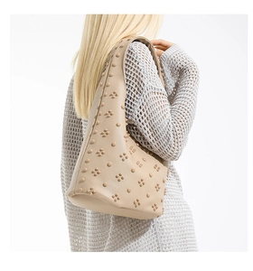 Detail of beige hobo bag with rivet studs on textured leather worn with knitwear
