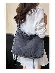 Borsa hobo in denim grigio scuro con bordi sfrangiati mostrata su un modello