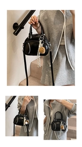 Detail of a black leather baseball-themed bag with white stitching and glove charm accessory