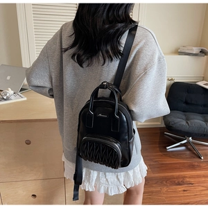 Detail of black pleated backpack featuring textured front pocket and quality leather finish