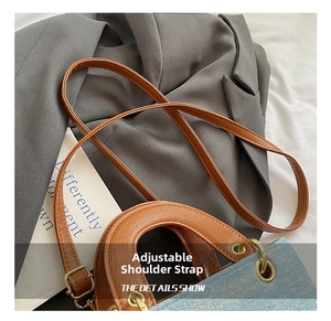 Detail of adjustable brown leather shoulder strap on a blue denim square handbag