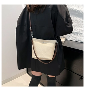 Détail d'un sac bandoulière tissé crème avec texture premium et sangle en cuir brun