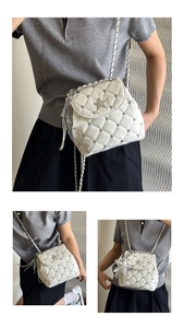 Detail of white quilted crossbody bag with silver star emblem and chain strap