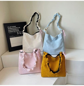 Detail of four colorful suede tote bags showing pleated shoulder straps and soft textures