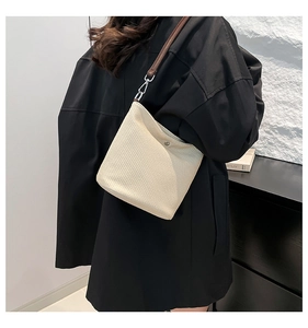 Détail du sac tressé crème avec bandoulière en cuir marron et boucles en métal argenté