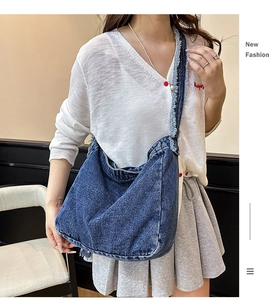 Dettaglio della borsa a tracolla in denim blu con bordi sfrangiati e tracolla larga regolabile