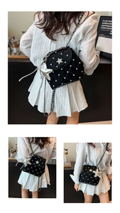 Detail of black quilted leather shoulder bag with silver star studs and crystal accents