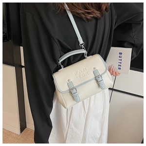 Detailed view of bicolor crossbody bag with dual buckle straps and embossed lettering