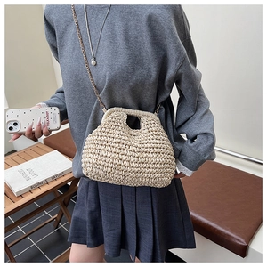Détail d'un sac en paille tressé main crème avec texture et bandoulière en chaîne dorée