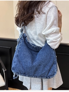 Dettaglio della borsa tote in denim lavato blu scuro con eleganti bordi sfilacciati