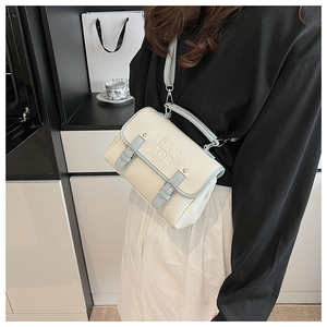 Lifestyle shot of a small beige and light blue flap handbag with PAN TOR logo detail